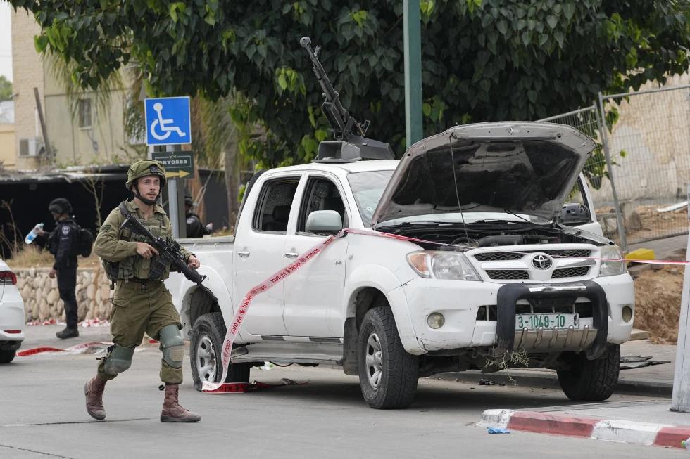 FILE - An Israeli soldier walks by a pickup truck used by Palestinian militants in Sderot, Israel, on Saturday, Oct. 7, 2023. (AP Photo)