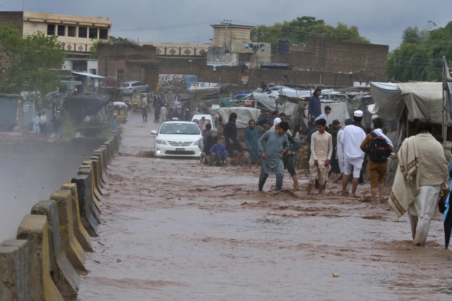 People wade through a flooded bridge on a stream, which is overflowing following heavy rains, on the outskirts of Peshawar, Pakistan, Monday, April 15, 2024. (AP/RSS Photo)
