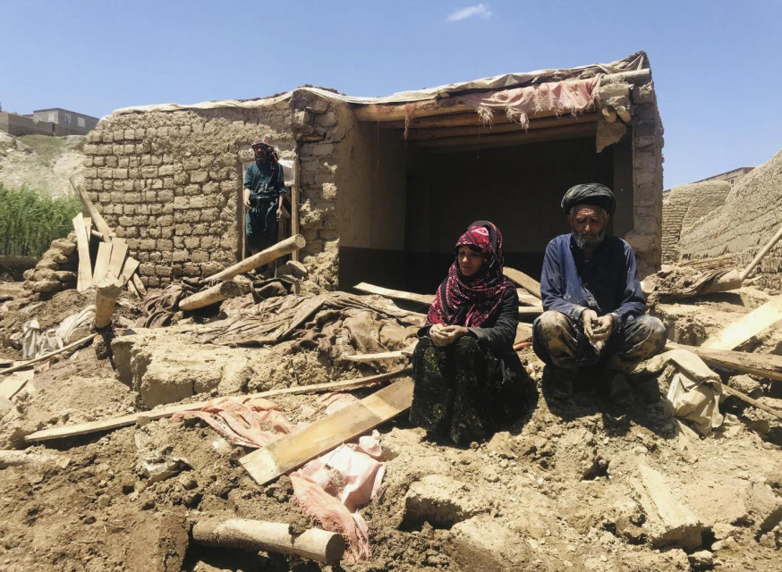 An Afghan couple sit near their damaged home after heavy flooding in Ghor province in western Afghanistan, Saturday, May 18, 2024. (AP Photo)