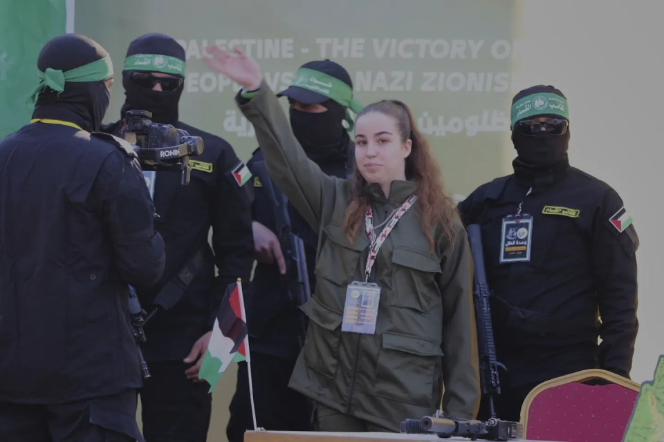 Israeli soldier Agam Berger waves to the crowd next to masked Islamic Jihad militants as she is handed over to the Red Cross at the Jabalya refugee camp in Gaza City, Thursday Jan. 30, 2025.(AP Photo)