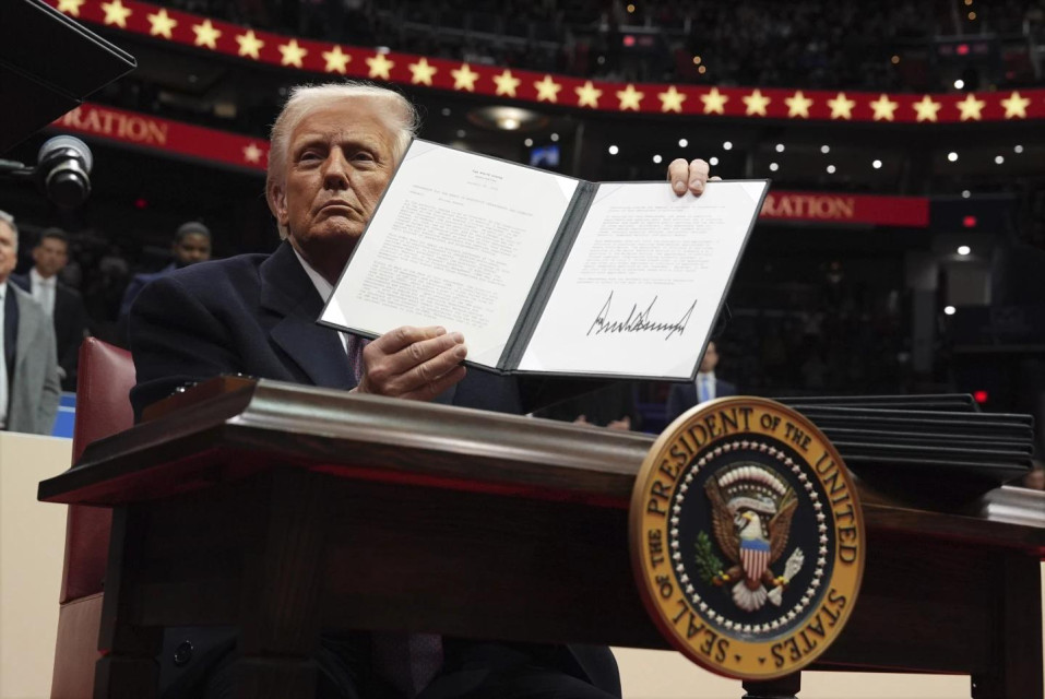 President Donald Trump signs an executive order as he attends an indoor Presidential Inauguration parade event at Capital One Arena, Monday, Jan. 20, 2025, in Washington. (AP Photo)