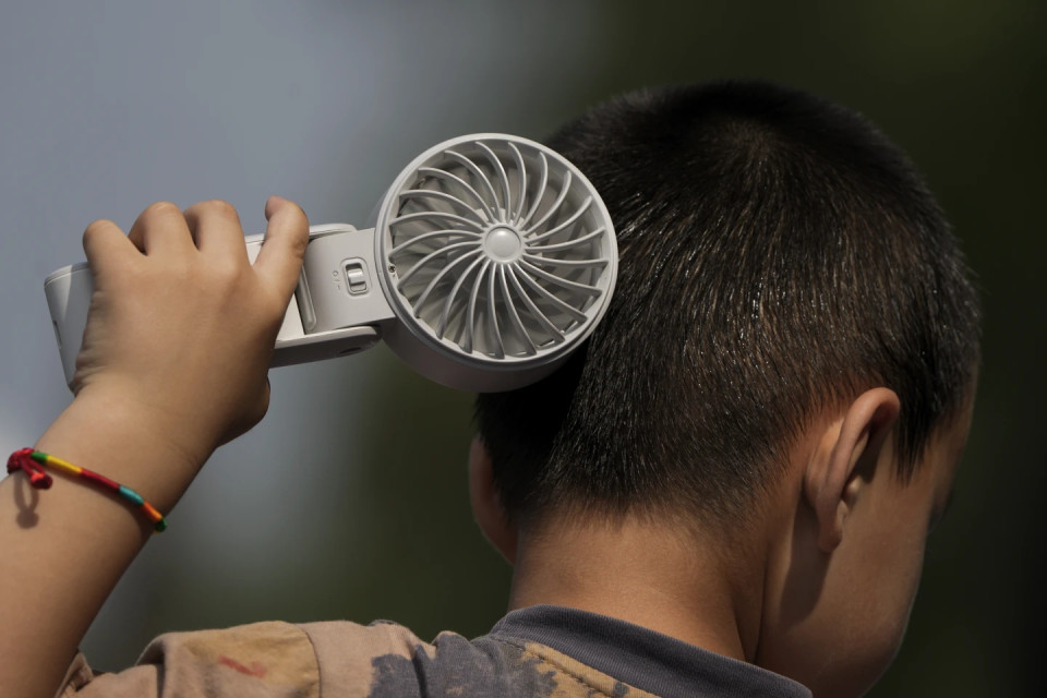 FILE - A boy cools himself with an electric fan on a sweltering day at a park in Tongzhou, on the outskirts of Beijing, Monday, June 10, 2024. AP/RSS Photo