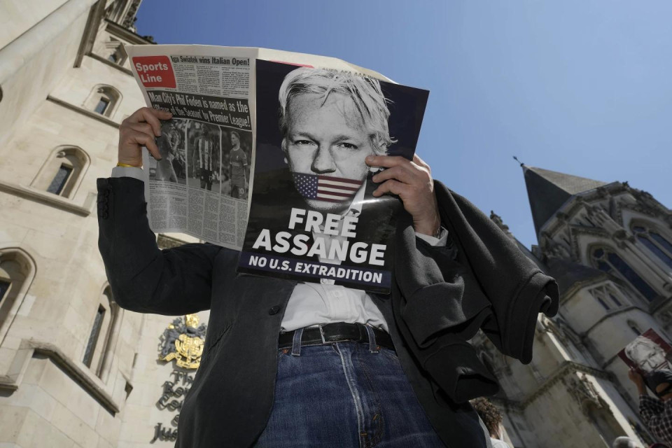 A protester reads a newspaper outside the High Court in London, Monday, May 20, 2024. (AP Photo)