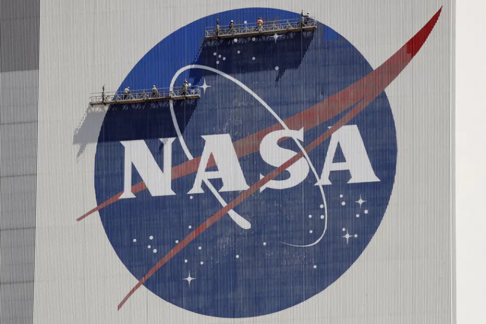FILE - Workers on scaffolding repaint the NASA logo near the top of the Vehicle Assembly Building at the Kennedy Space Center in Cape Canaveral, Florida, May 20, 2020. AP/RSS Photo