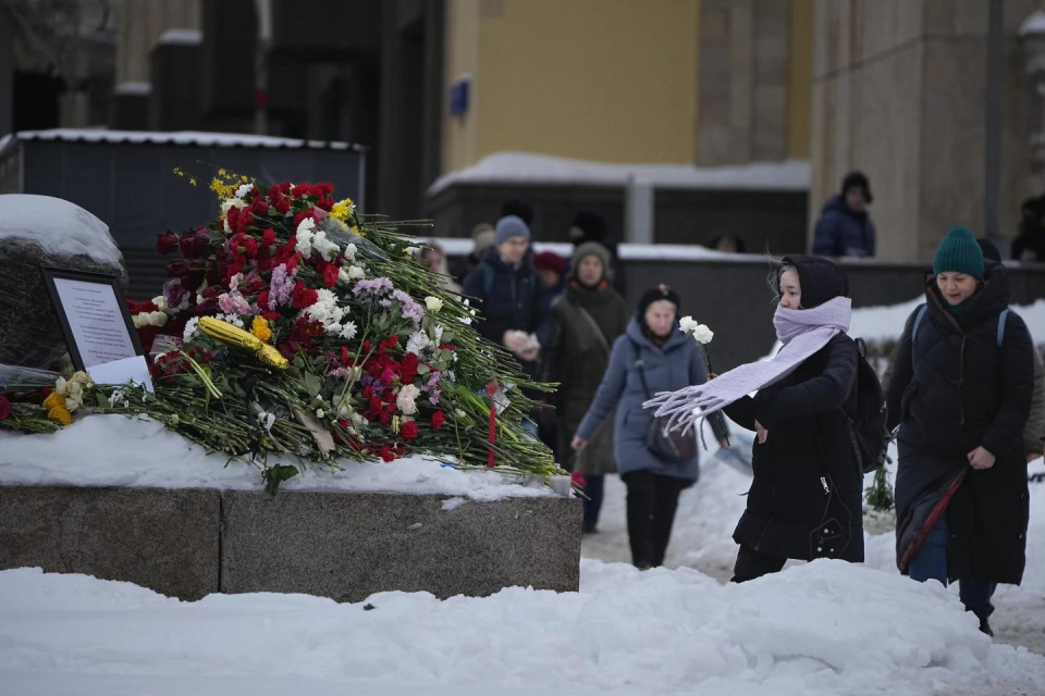 People lay flowers paying the last respect to Alexei Navalny at the monument, a large boulder from the Solovetsky islands, where the first camp of the Gulag political prison system was established, with the historical the Federal Security Service (FSB, Soviet KGB successor) building in the background, in Moscow, Russia, on Saturday morning, Feb. 17, 2024. (AP/RSS Photo)