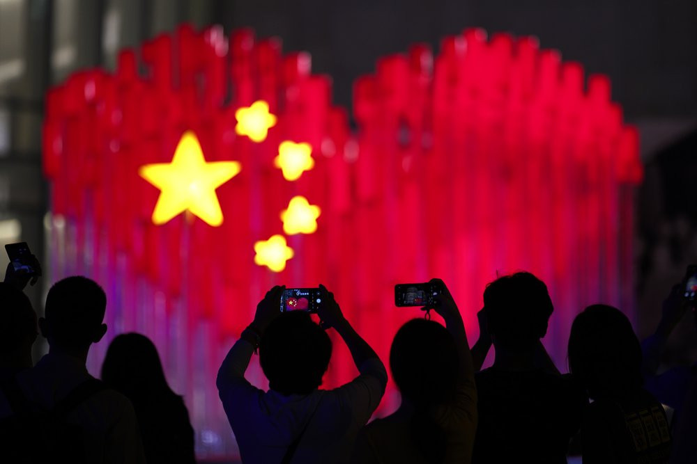 Visitors take photos with their smart phones of an installation depicting a heart shape Chinese national flag in Shanghai, China, Friday, Sept. 27, 2019. China will mark its 70th anniversary 
