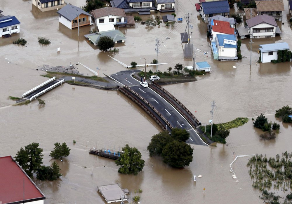 Cars are stranded on a road as the city is submerged in muddy waters after an embankment of the Chikuma River broke, in Nagano, central Japan, Sunday, Oct. 13, 2019.
