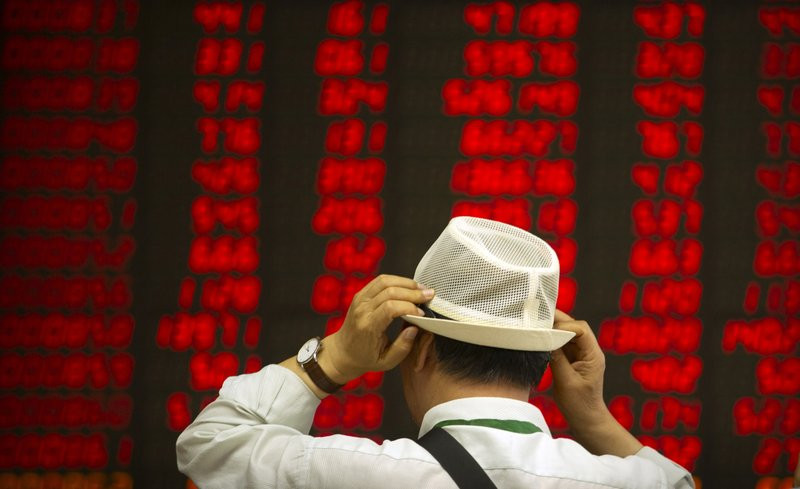 In this Sept. 5, 2019, file photo, an investor adjusts his hat as he monitors stock prices at a brokerage house in Beijing.