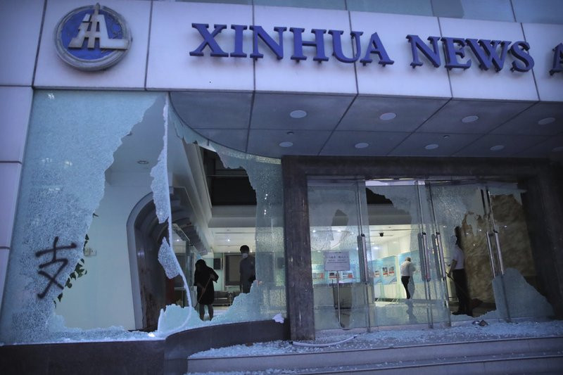 People stand inside the lobby of China's Xinhua News Agency damaged by protesters in Hong Kong, Saturday, Nov. 2, 2019.