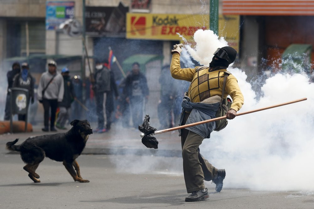 A backer of former President Evo Morales returns a tear gas canister to police during clashes in La Paz, Bolivia, Wednesday, Nov. 13, 2019.