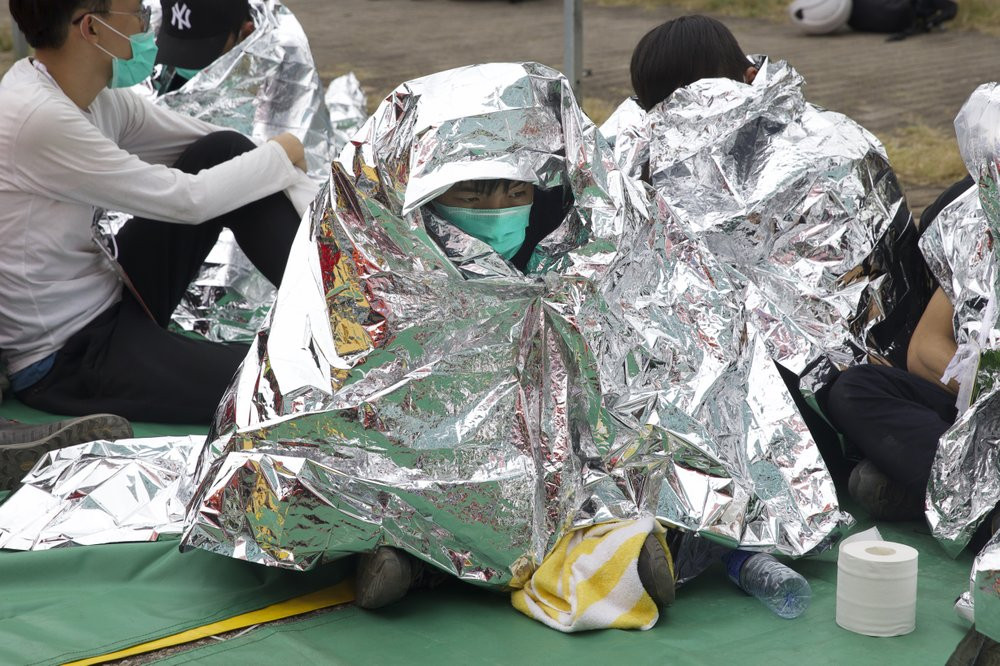 An injured youth sits under a space blanket at a casualty evacuation point near Hong Kong Polytechnic University in Hong Kong, Tuesday, Nov. 19, 2019.