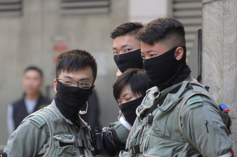 Riot police stand outside of a polling place in Hong Kong, Sunday, Nov. 24, 2019. Voting was underway Sunday in Hong Kong elections that have become a barometer of public support for anti-gov