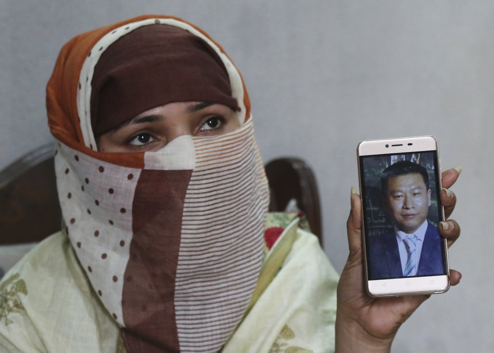 In this May 22, 2019 file photo, Sumaira a Pakistani woman, shows a picture of her Chinese husband in Gujranwala, Pakistan.