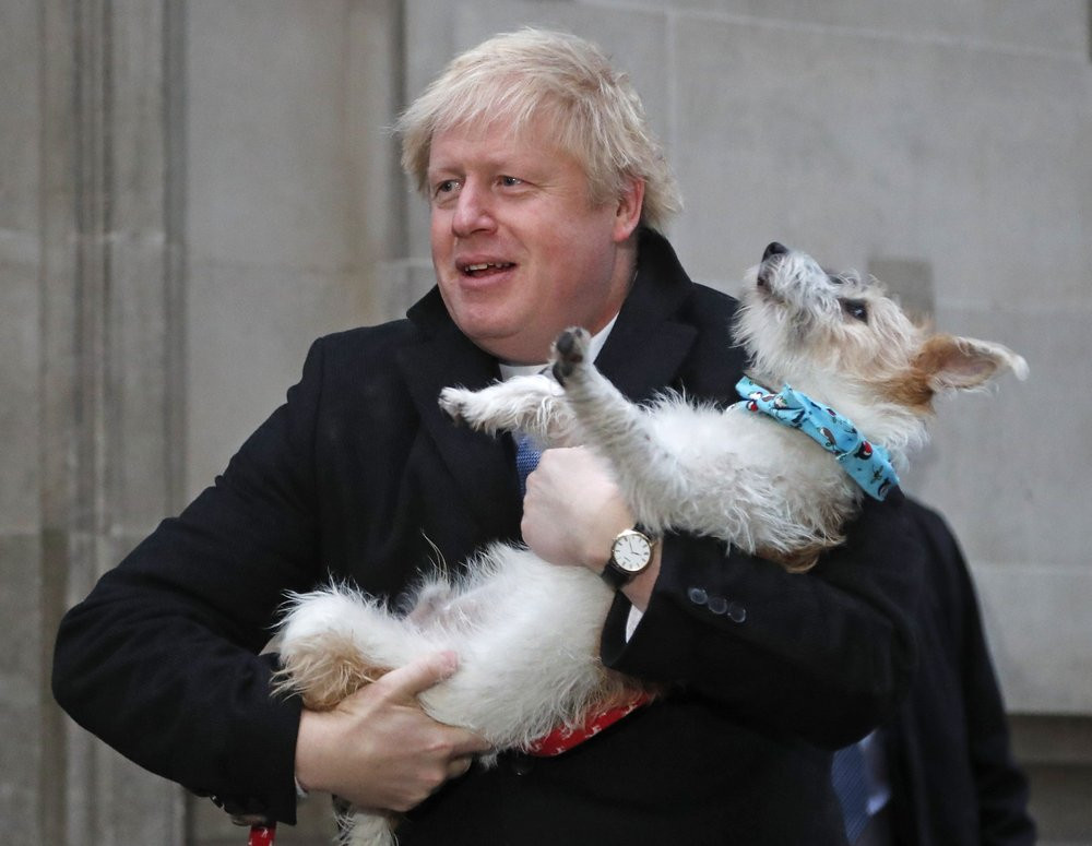 Britain's Prime Minister and Conservative Party leader Boris Johnson holds his dog Dilyn as he leaves after voting in the general election at Methodist Central Hall, Westminster, London, Thur