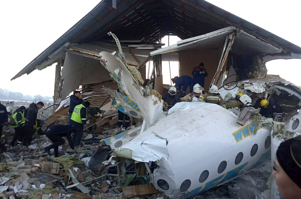 In this handout photo provided by the Emergency Situations Ministry of the Republic of Kazakhstan, police and rescuers work on the side of a plane crash near Almaty International Airport, out