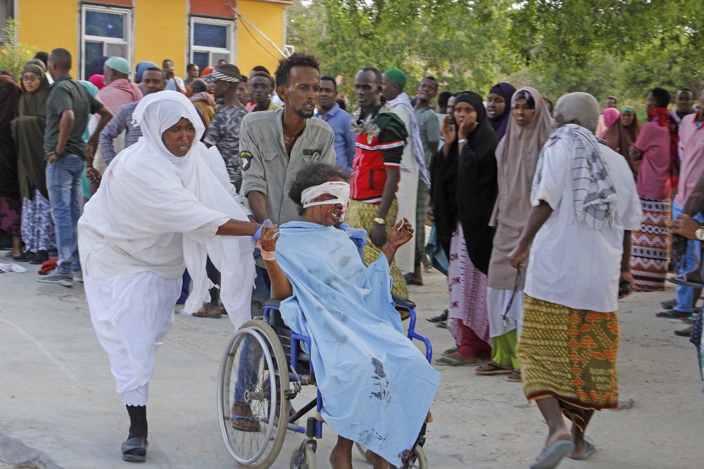 A civilian who was wounded in suicide car bomb attack is helped to be taken to hospital in Mogadishu, Somalia, Saturday, Dec, 28, 2019.