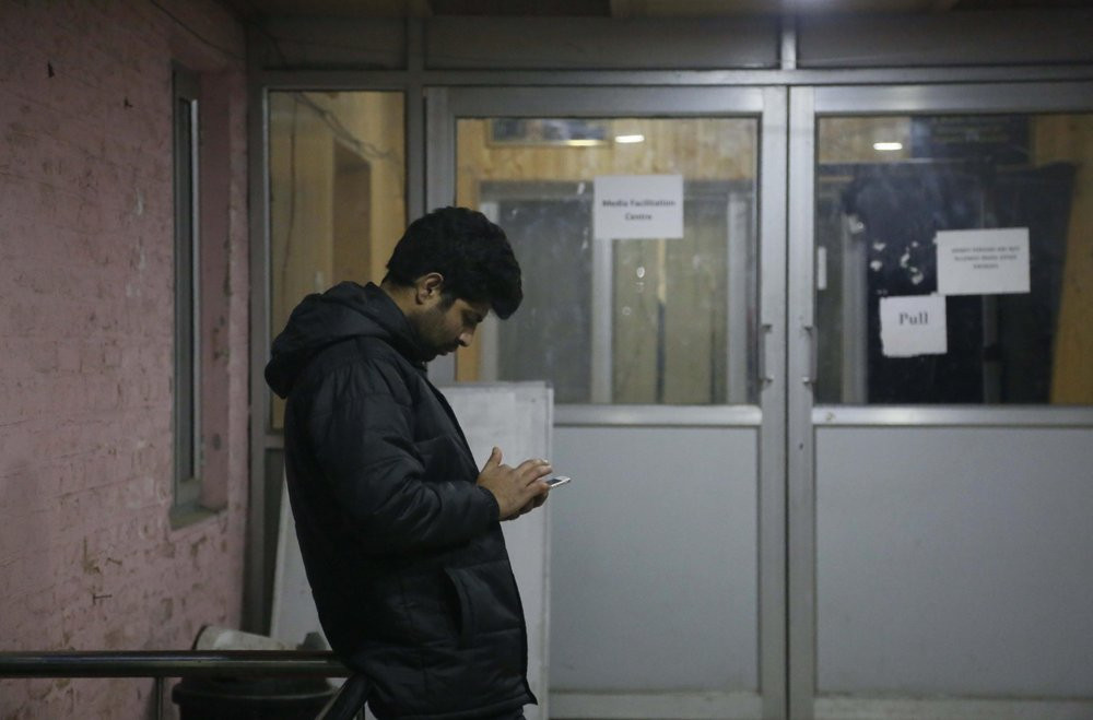 A man checks his cellphone outside a media facilitation centre in Srinagar, Indian controlled Kashmir, Tuesday, Dec. 31, 2019.
