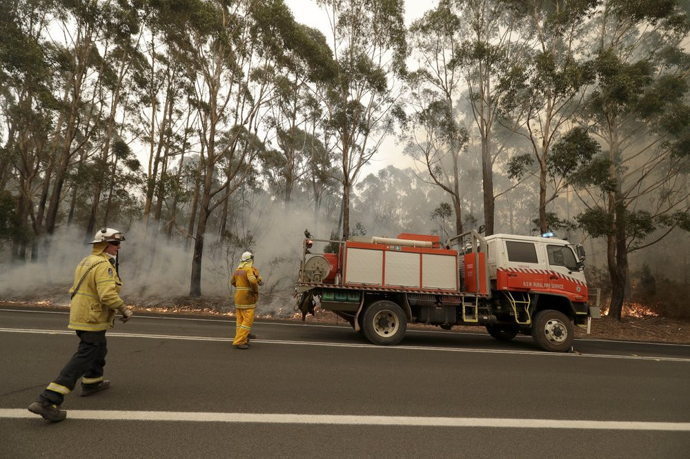 A firefighting crew battles a fire near Burrill Lake, Australia, Sunday, Jan. 5, 2020. Milder temperatures Sunday brought hope of a respite from wildfires that have ravaged three Australian s