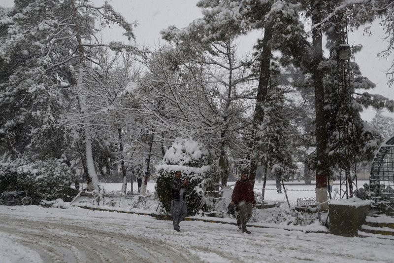 In this Sunday, Jan. 12, 2020, photo, people walk on a road during heavy snow fall in Quetta, capital of Pakistan's southwestern Baluchistan province.