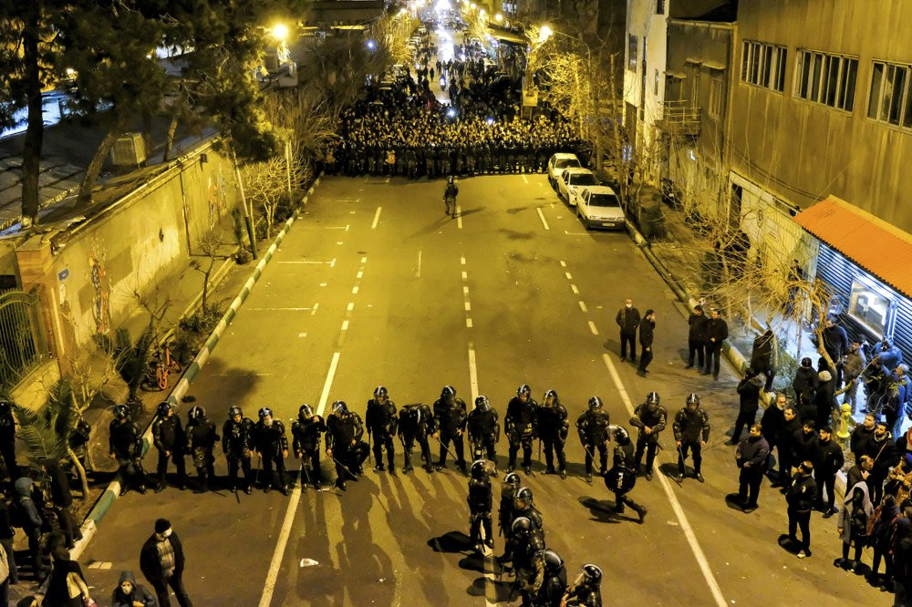 In this photograph taken Saturday, Jan. 11, 2020, Iranian police officers take position while protesters gather in front of Amir Kabir University in Tehran, Iran, to remember victims of a Ukr