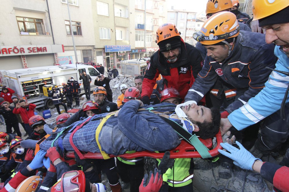 Rescue workers carry a wounded man that was found alive in the rubble of a building destroyed on Friday's earthquake in Elazig, eastern Turkey, Saturday, Jan. 25, 2020.