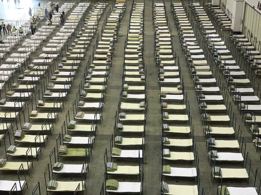 Workers arrange beds in a convention center that has been converted into a temporary hospital in Wuhan in central China's Hubei Province, Tuesday, Feb. 4, 2020.