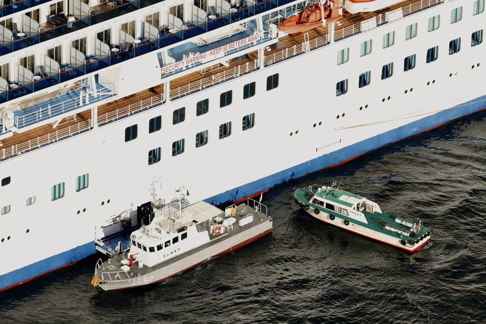 Japan Coast Guard's patrol boat, left, is brought alongside the cruise ship Diamond Princess to take passengers tested positive for coronavirus to hospitals off Yokohama, south of Tokyo, Wedn