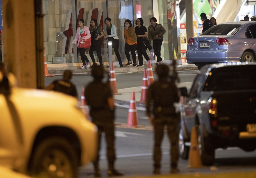 People who were able to get out of Terminal 21 Korat mall walk outside the building in Nakhon Ratchasima, Thailand on Sunday, Feb. 9, 2020.