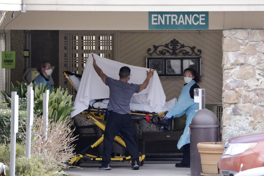 A person is taken by stretcher to a waiting ambulance from a nursing facility where more than 50 people are sick and being tested for the COVID-19 virus, Saturday, Feb. 29, 2020, in Kirkland,