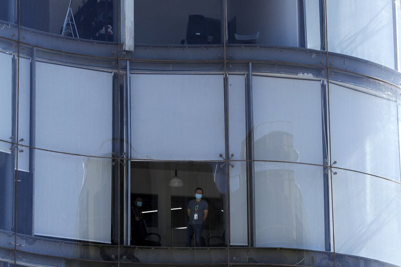 A masked worker looks out from his office in Beijing, Tuesday, March 10, 2020.