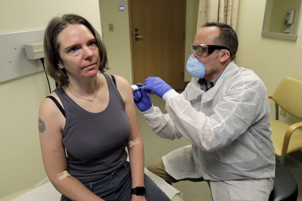 A pharmacist gives Jennifer Haller, left, the first shot in the first-stage safety study clinical trial of a potential vaccine for COVID-19on Monday at the Kaiser Permanente Washington Health