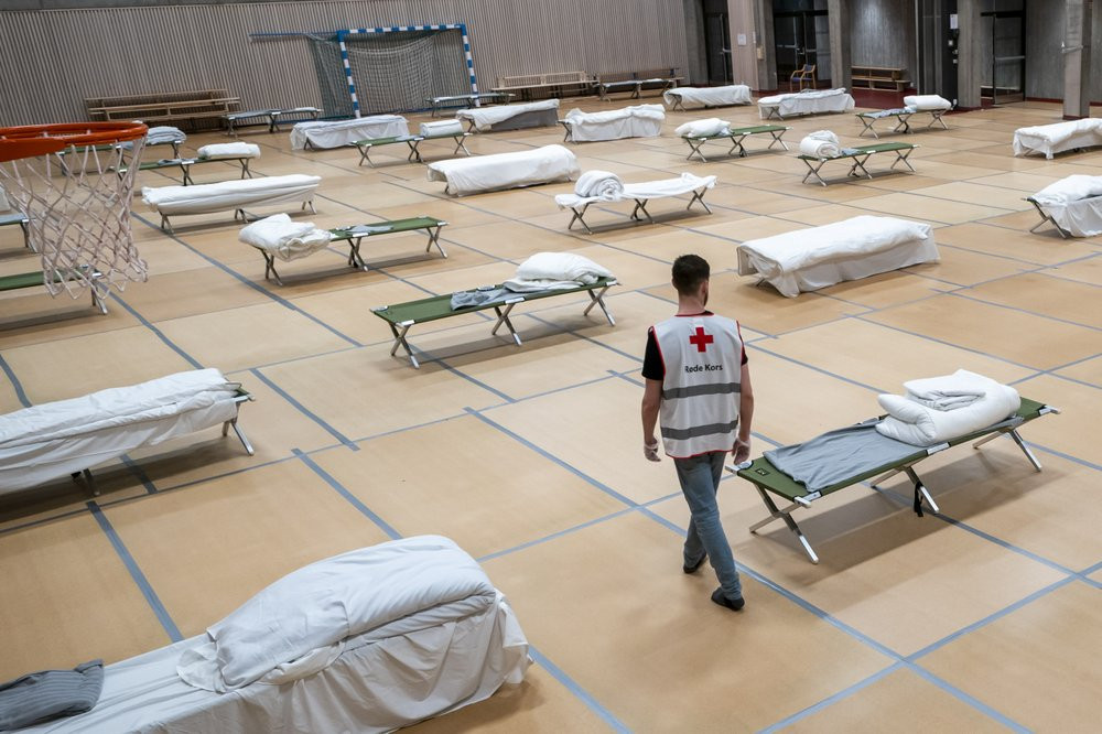 A Red Cross volunteer looks at beds set up for homeless people in the gymnasium of Uranienborg school, which is closed due to the corona eruption, in Oslo, Thursday, March 26, 2020.