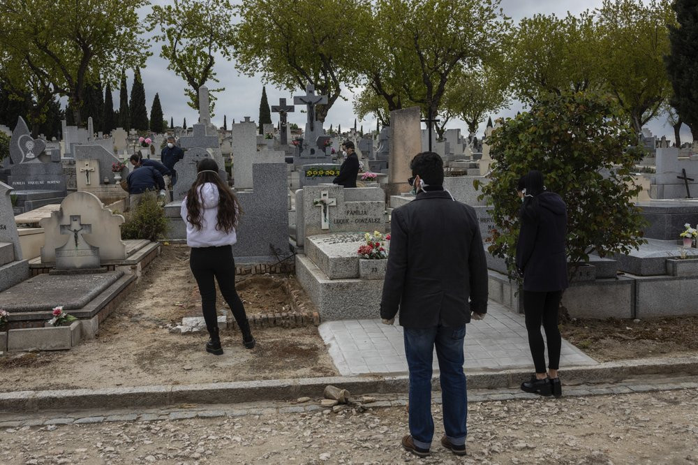 Relatives wearing face masks to protect against coronavirus, observe social distancing guidelines during a burial at a Madrid cemetery during the coronavirus outbreak in Madrid, Spain, Friday