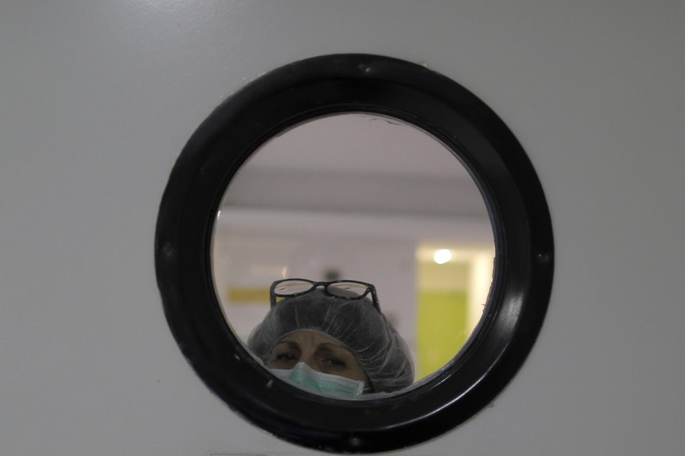 A health worker wearing a face mask to protect from coronavirus, looks out of from a window at a nursing home in Madrid, Spain, Tuesday, March 31, 2020.