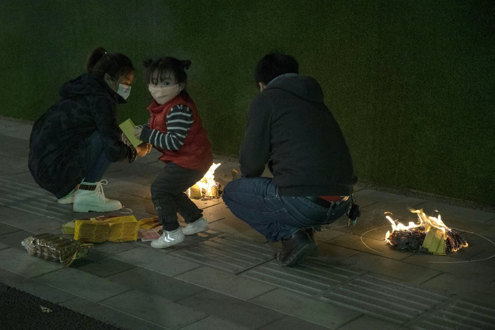 A family burn paper offerings for their departed relatives on the streets of Wuhan in central China's Hubei province on Saturday, April 4, 2020.