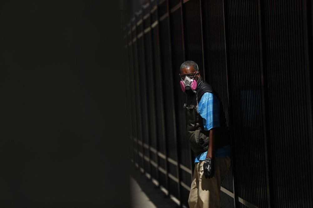 A man wears a protective mask while waiting for a bus in Detroit, Wednesday, April 8, 2020. Detroit buses will have surgical masks available to riders starting Wednesday, a new precaution the