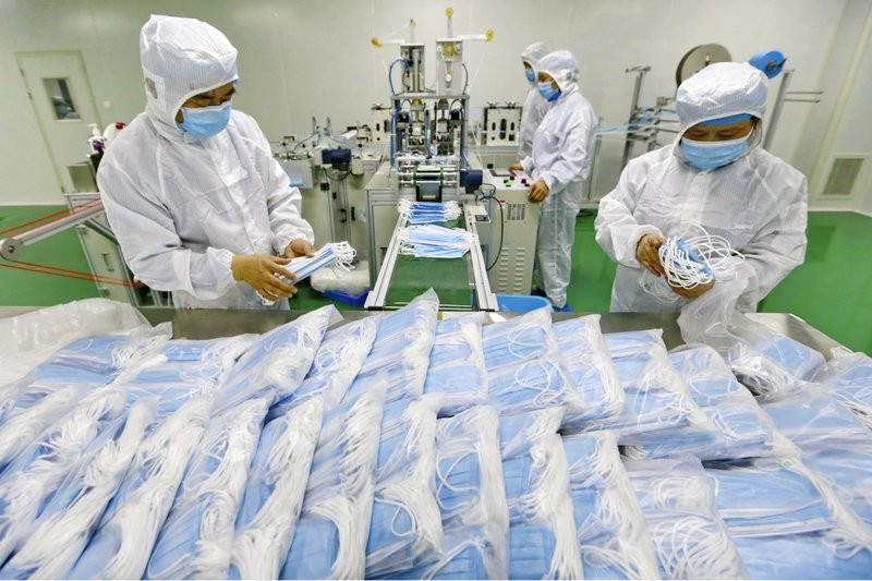 In this Feb. 7, 2020 file photo, workers pack surgical masks at a factory in Suining city in southwest China's Sichuan province.