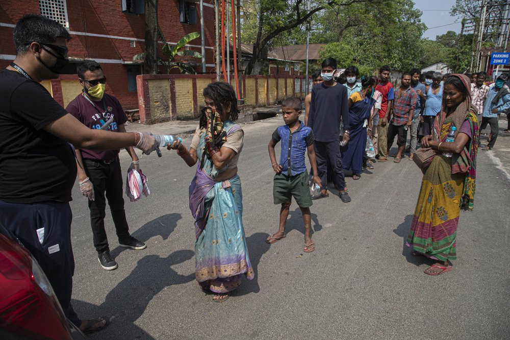 A group of Indians distribute free food and water to homeless people during a nationwide lockdown to curb the spread of new coronavirus in Gauhati, India, Sunday, April 19, 2020.