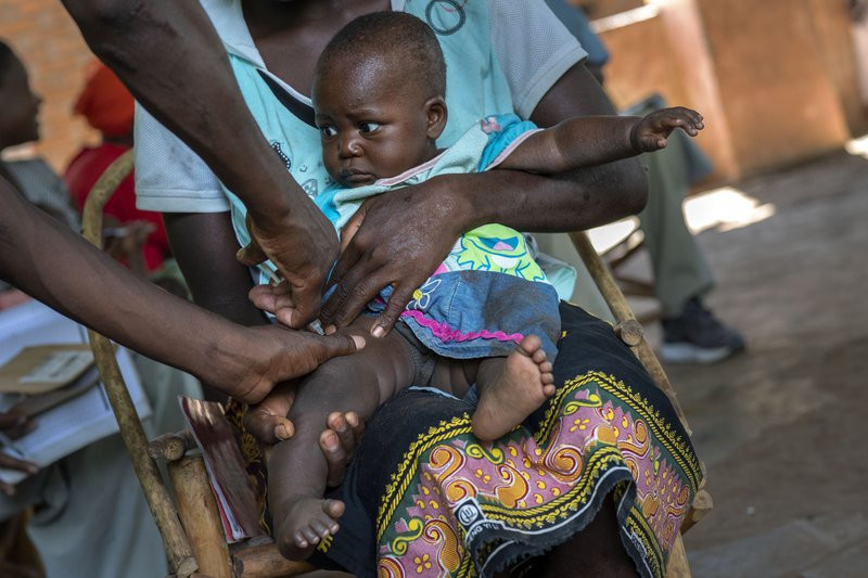 In this photo taken Wednesday, Dec. 11, 2019, health officials vaccine residents of the Malawi village of Tomali, where young children become test subjects for the world's first vaccine again