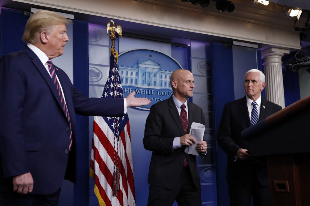 President Donald Trump gestures to Vice President Mike Pence as Stephen Hahn, commissioner of the U.S. Food and Drug Administration, steps back to the podium to answer a question during a bri