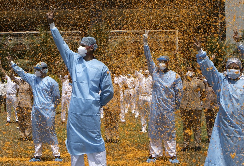 An Indian Air Force helicopter showers flower petals on the staff of INS Asvini hospital in Mumbai, India, Sunday, May 3, 2020.
