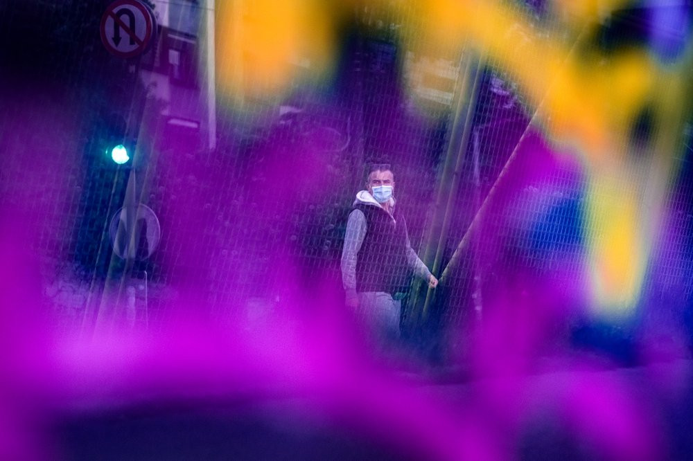 Seen through a bridge glass panel covered in graffiti a man wearing a face mask walks in Sarajevo, Bosnia, Wednesday, May 6, 2020.