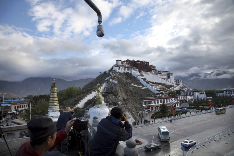 In this Sept. 19, 2015, file photo, tourists take photos of the Potala Palace beneath a security camera in Lhasa, capital of the Tibet Autonomous Region of China.