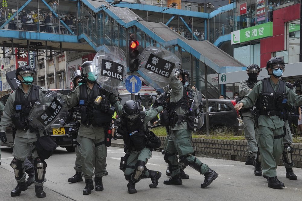 Riot police cover themselves with shields as hundreds of protesters march along a downtown street during a pro-democracy protest against Beijing's national security legislation in Hong Kong, 
