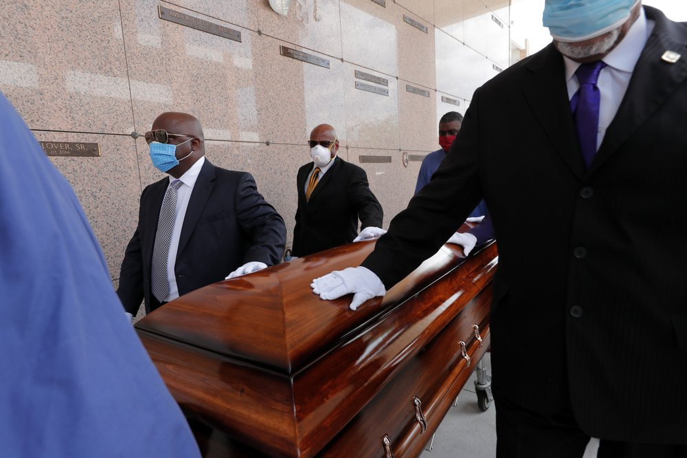 In this April 22, 2020, file photo, pallbearers, who were among only 10 allowed mourners, walk the casket for internment at the funeral for Larry Hammond, who died from the coronavirus, at Mo