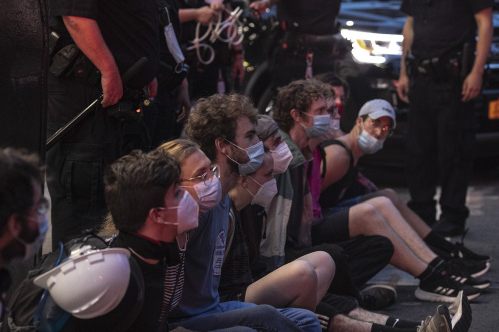 Protesters who were arrested by police for breaking a curfew during a solidarity rally calling for justice over the death of George Floyd, sit on a sidewalk as they wait to be taken away in a