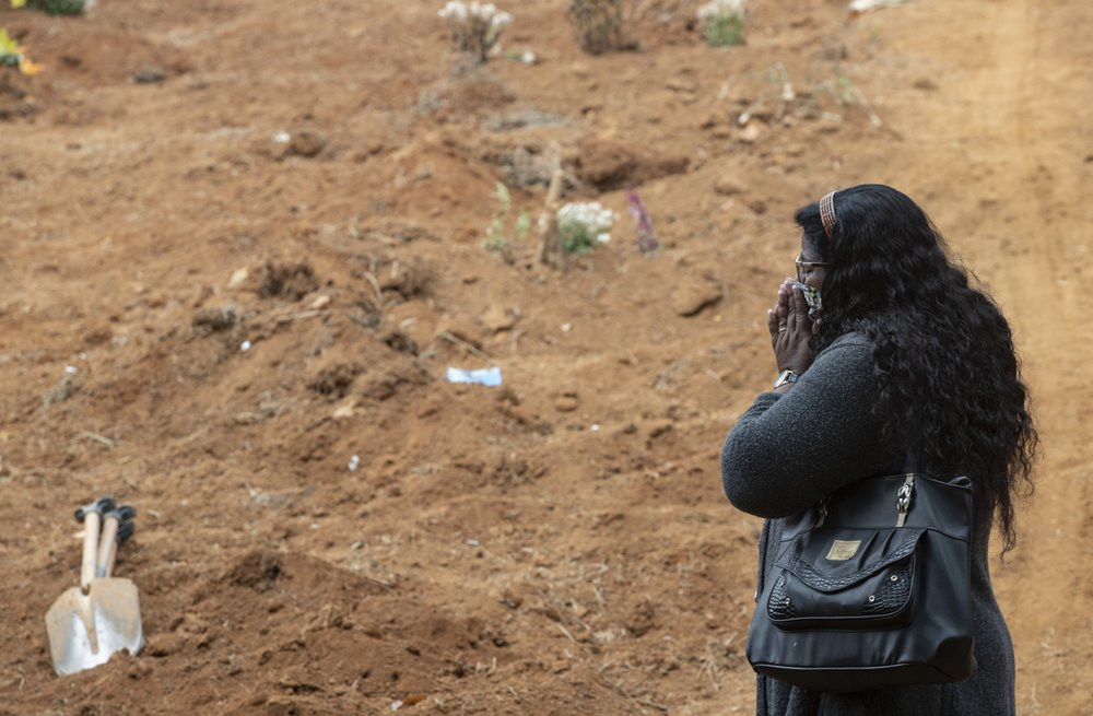 Vera Lucia Souza stands before at the gravesite of her 47-year-old brother Paulo Roberto da Silva, who died of COVID-19, during his burial at the Sao Luiz cemetery in Sao Paulo, Brazil, Thurs