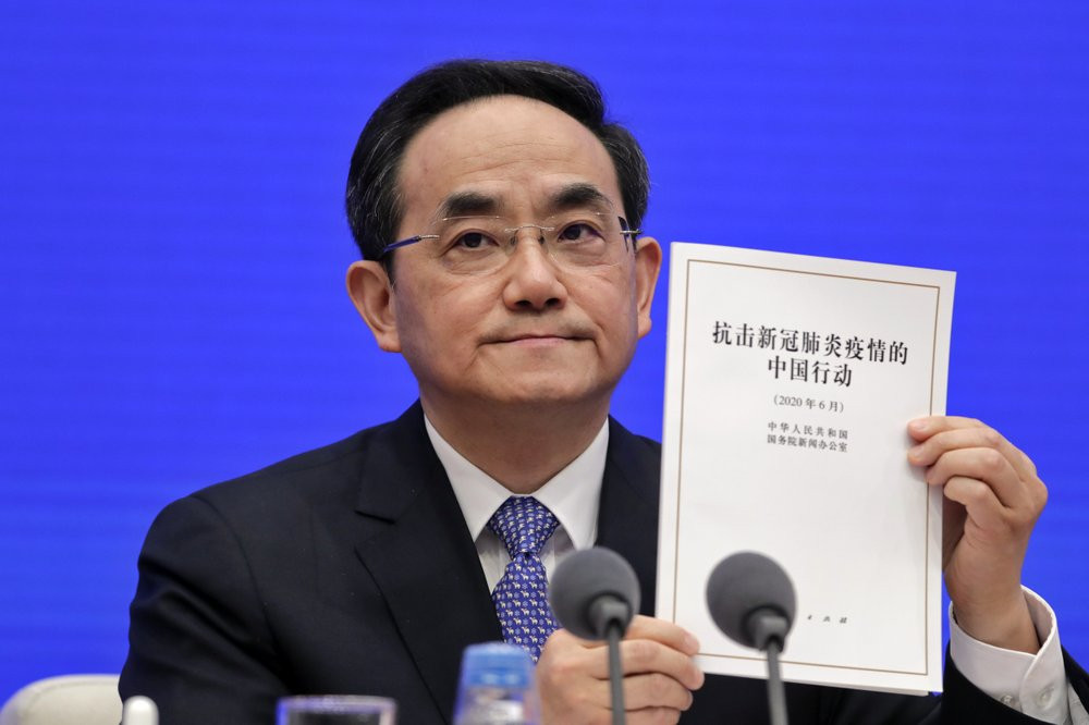 Xu Lin, Vice head of the Publicity Department of Communist Party shows a copy of the white paper on fighting COVID-19 China in action during a press conference at the State Council Informatio
