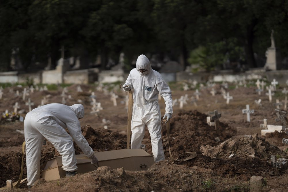 Cemetery workers in protective clothing maneuver the coffin of 57-year-old Paulo Jose da Silva, who died from the new coronavirus, in Rio de Janeiro, Brazil, Friday, June 5, 2020.