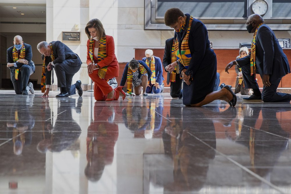 House Speaker Nancy Pelosi and other members of Congress, kneel and observe a moment of silence at the Capitol's Emancipation Hall Monday on Capitol Hill in Washington, reading the names of G